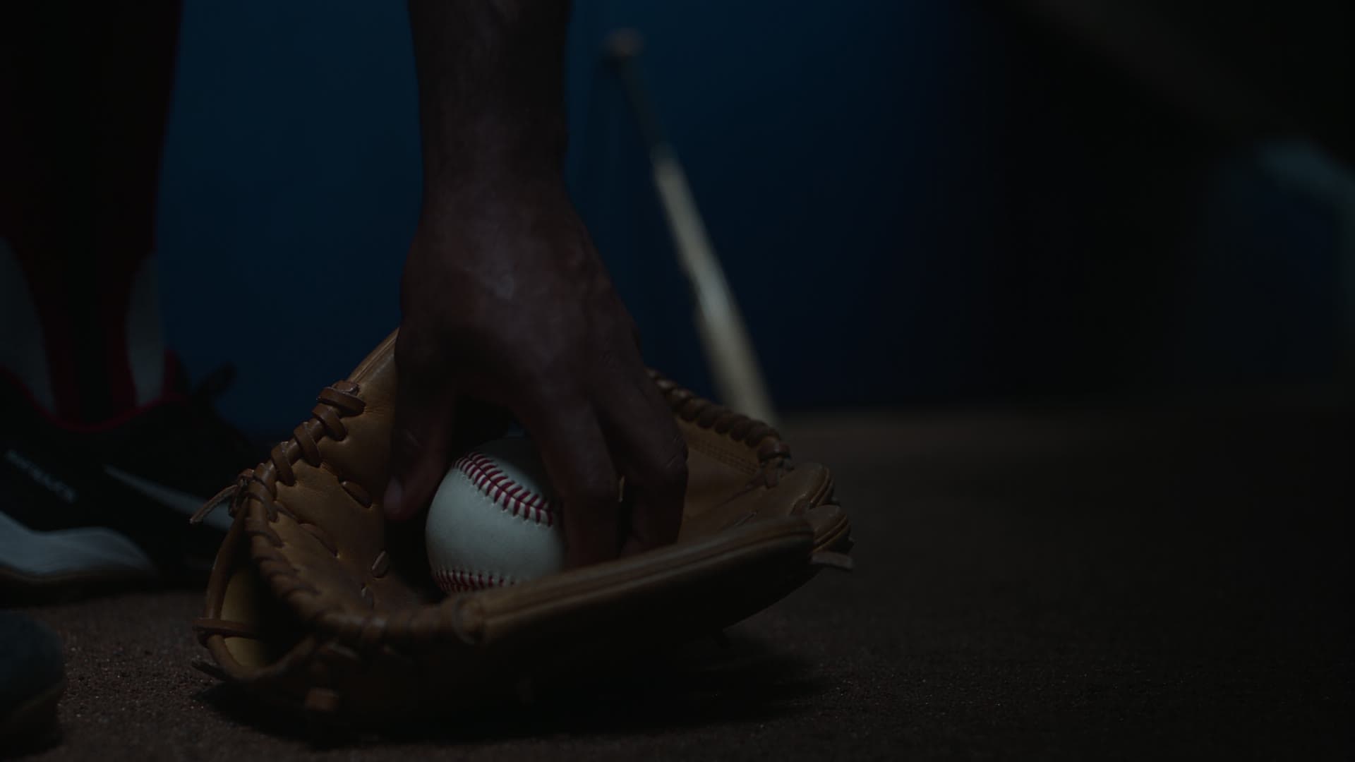 Guante y pelota de béisbol en una escena oscura